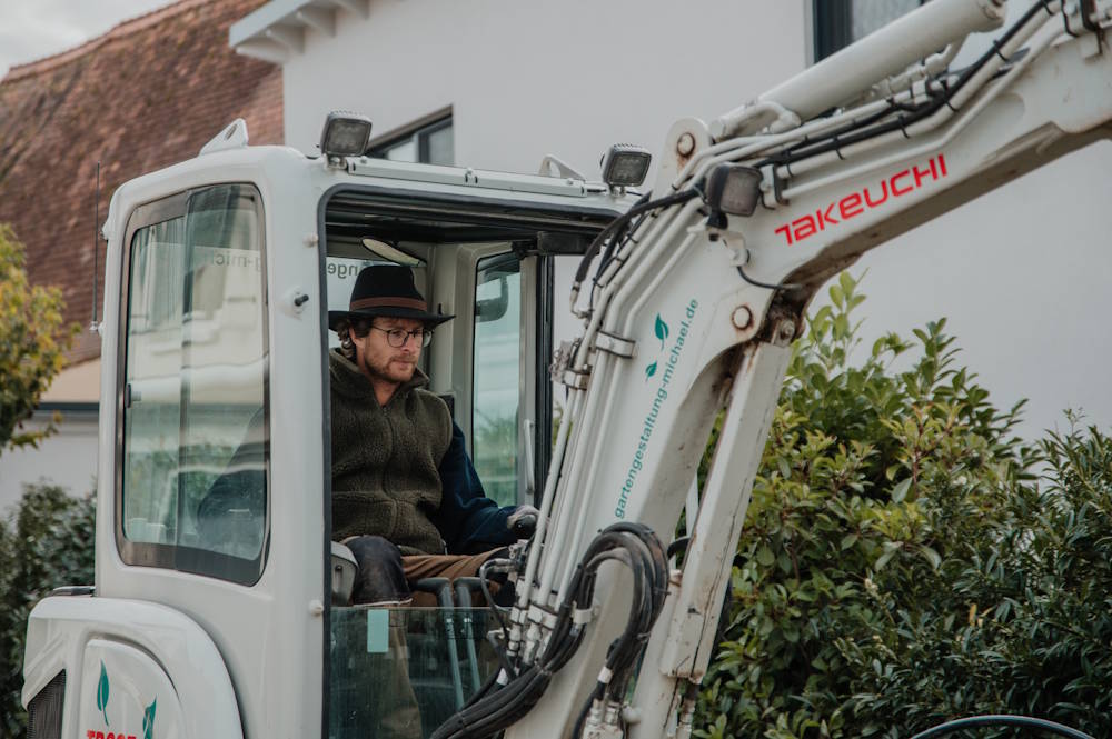 Chef Michael steuert Bagger bei Arbeiten im Garten und Landschaftsbau