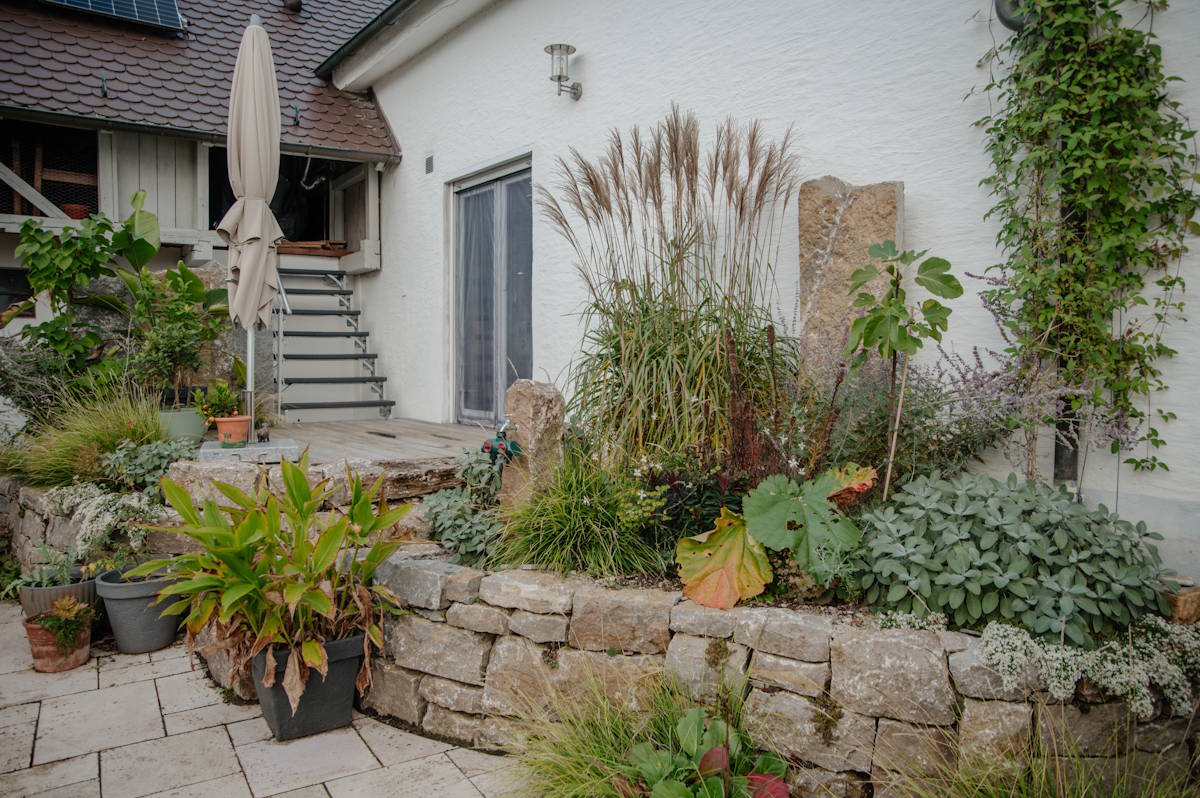 Garten mit Natursteinmauer, Terrasse und abgestimmter Bepflanzung am Haus