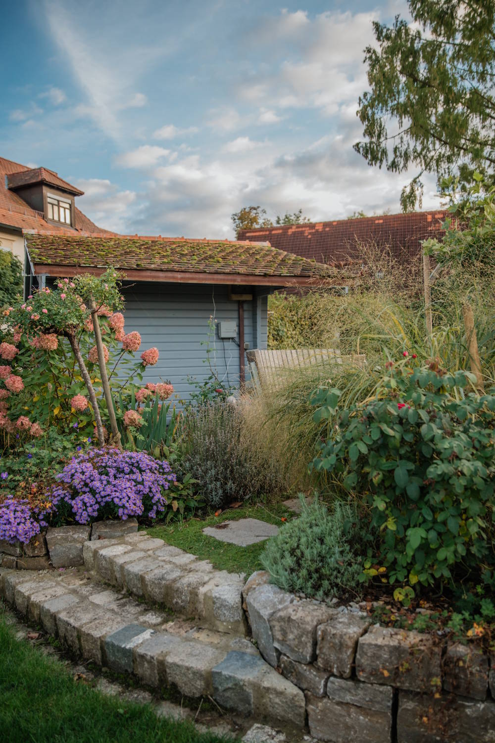 Garten mit Natursteinmauer, Terrasse und abgestimmter Bepflanzung