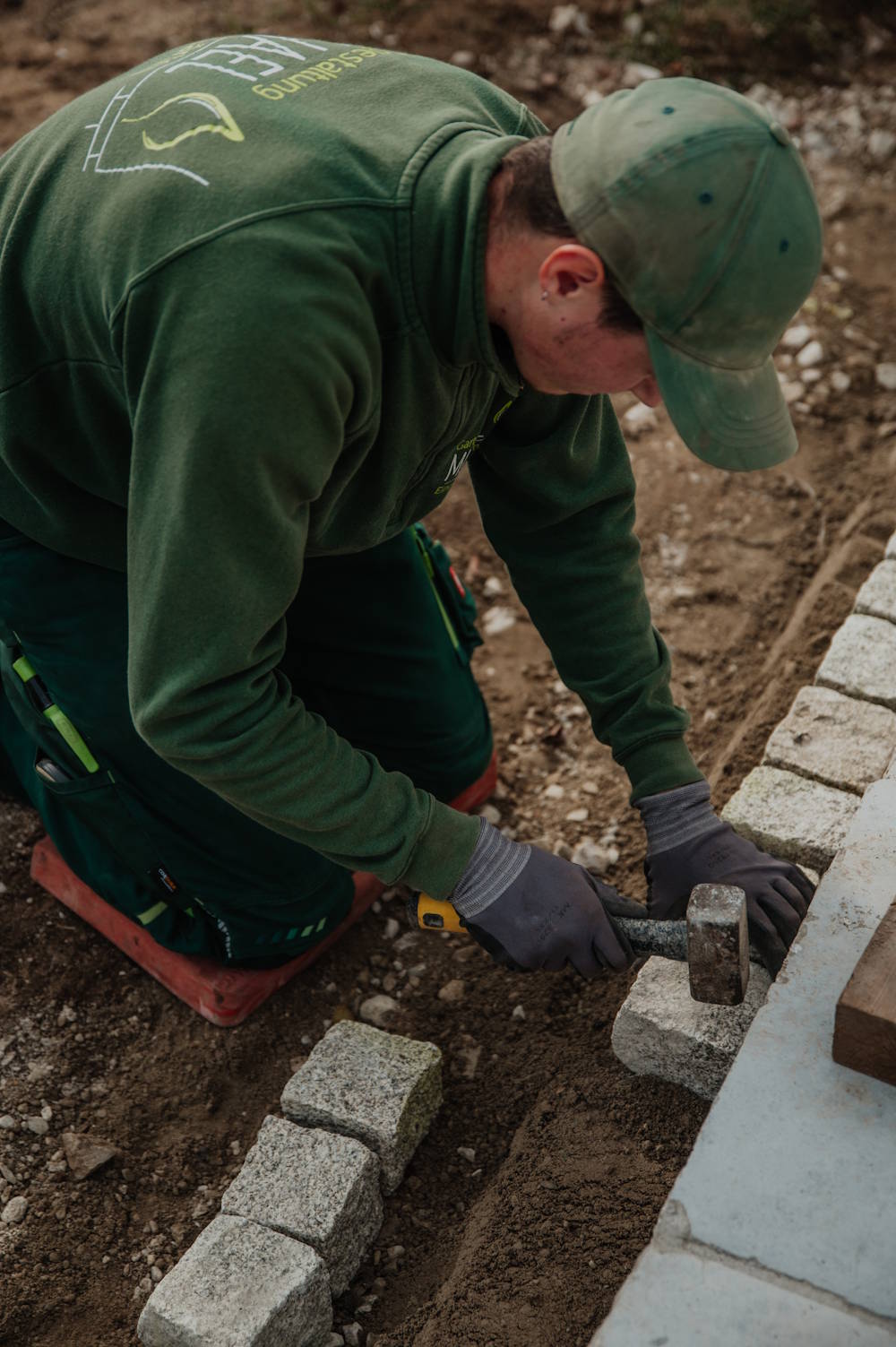 Mitarbeiter setzt Natursteine von Hand im Gartenbau
