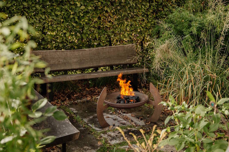 gemütliche Ecke im Garten mit Holzbank und einer Feuerschale