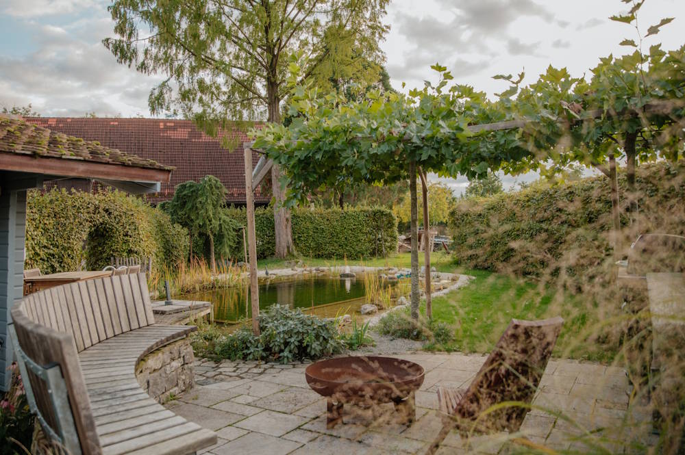 Individuell gestalteter Garten mit Teich, Sitzplatz und strukturierter Bepflanzung