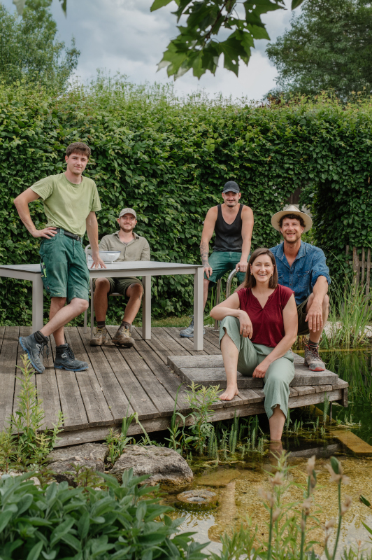 Team sitz lächelnd auf Holzterrasse beim Schwimmreich