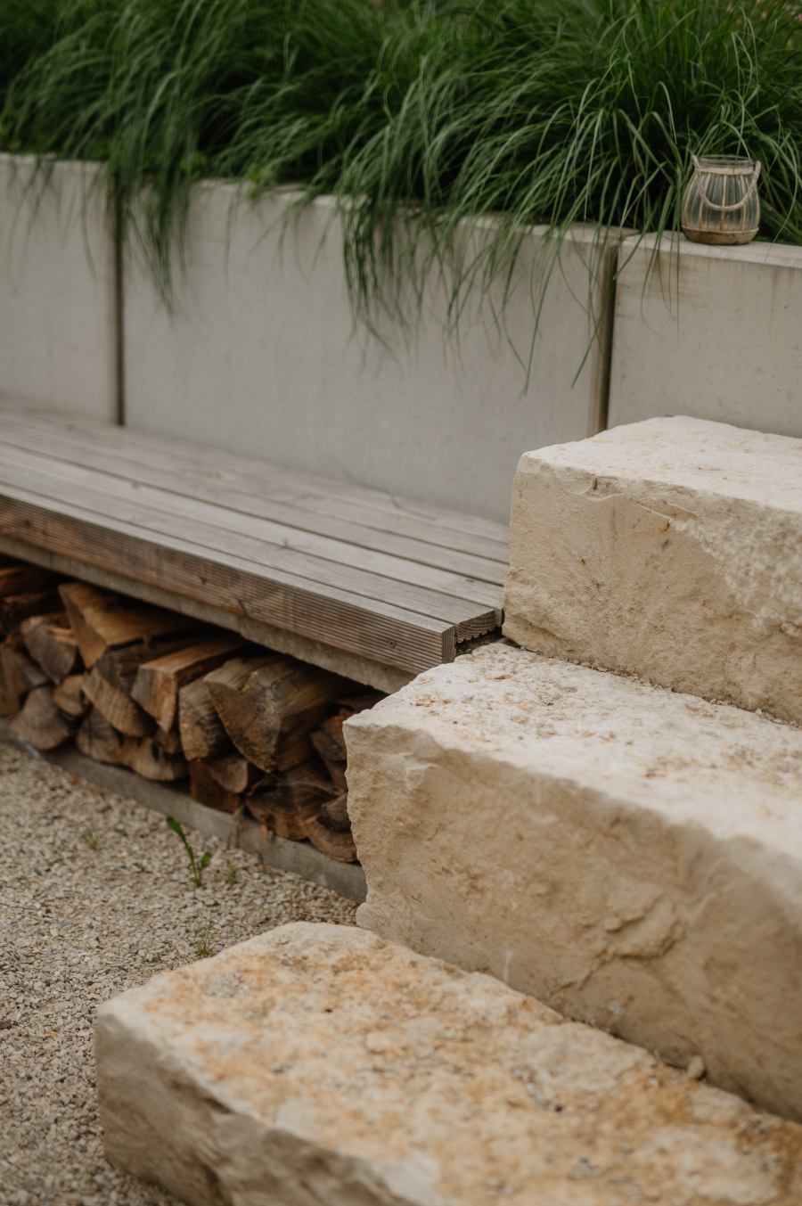 Naturstein-Blockstufen aus Muschelkalk neben einer modernen Beton-Sitzbank mit Holzlager-Nische.