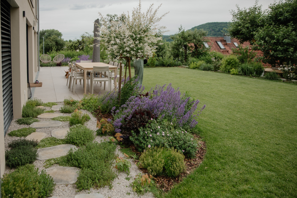 Trittplatten im Kiesweg und Blick auf modere, bepfanzte Terrasse